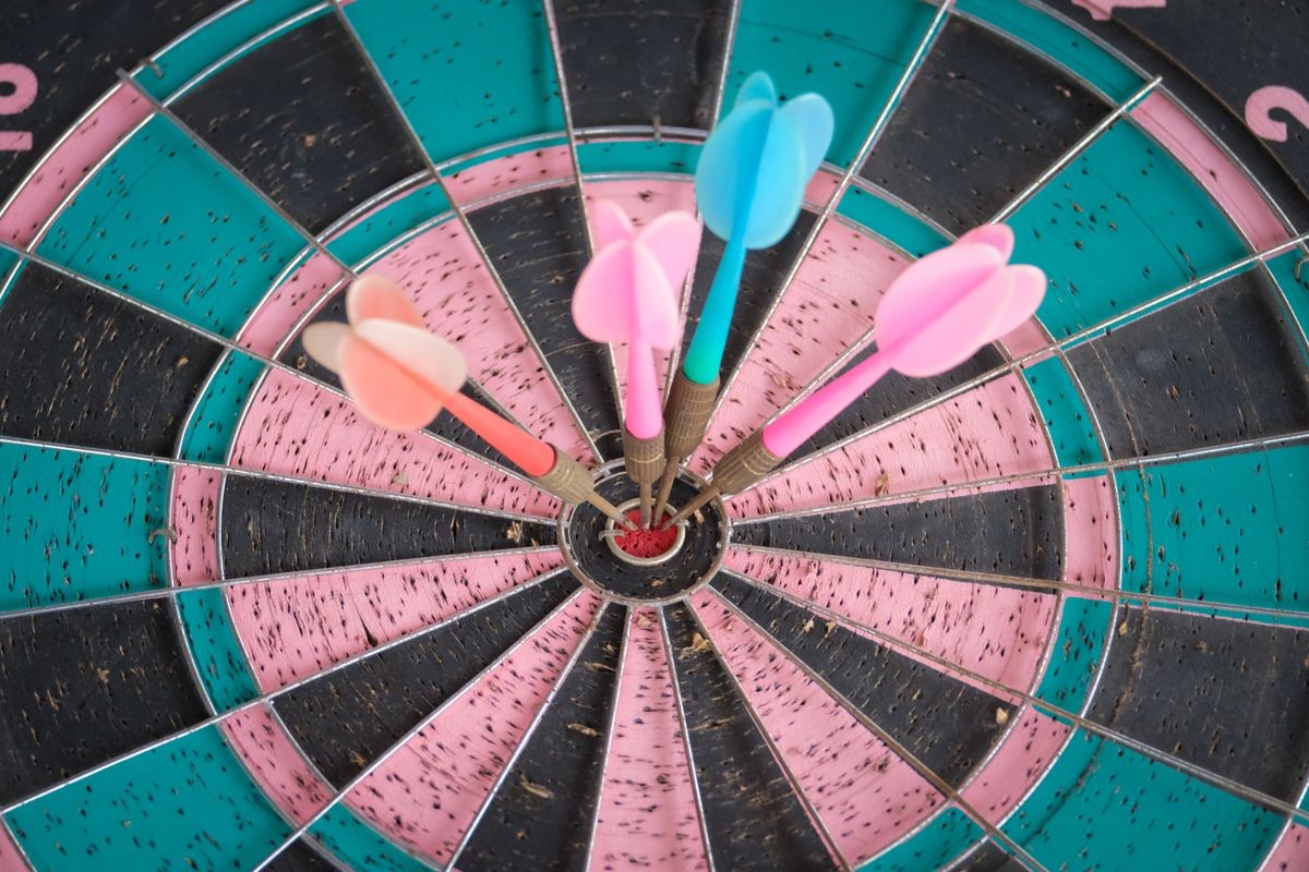 four darts arrows hitting in the target center dartboard. Success business goal concept
